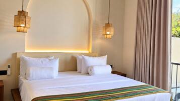 Habitación de hotel con una cama grande, dos lámparas de noche, un aire acondicionado y vistas al exterior.