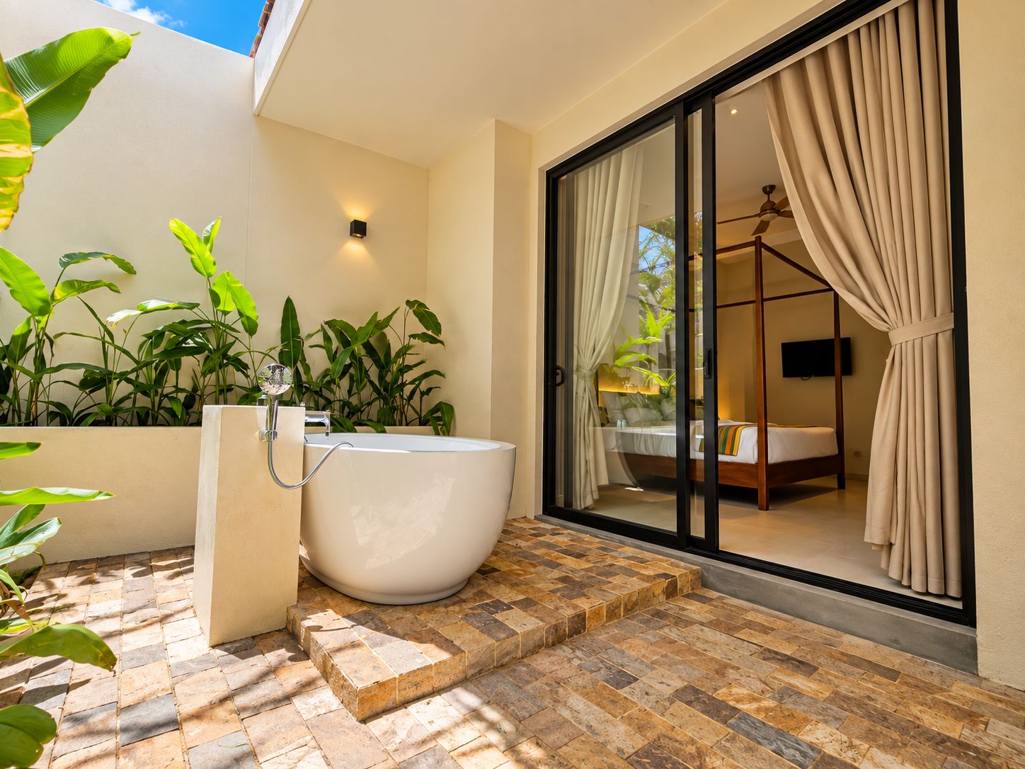 Une salle de bain moderne avec une baignoire sur pieds, une douche et une chambre séparée par des parois de verre et dotée de rideaux.