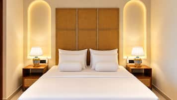 Un dormitorio moderno de hotel con una cama grande, cabecera de madera, dos mesitas de noche con lámparas, un equipo de aire acondicionado y un ventilador de techo.