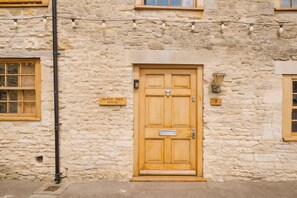 A stone building with a wooden door, a mailbox, and a number plate. - Beautiful 4BD Cottage in Minchinhampton (Minchinhampton)