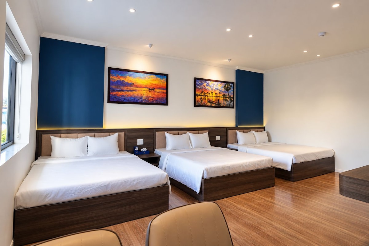 A hotel room with two beds, a desk, and artwork on the walls.