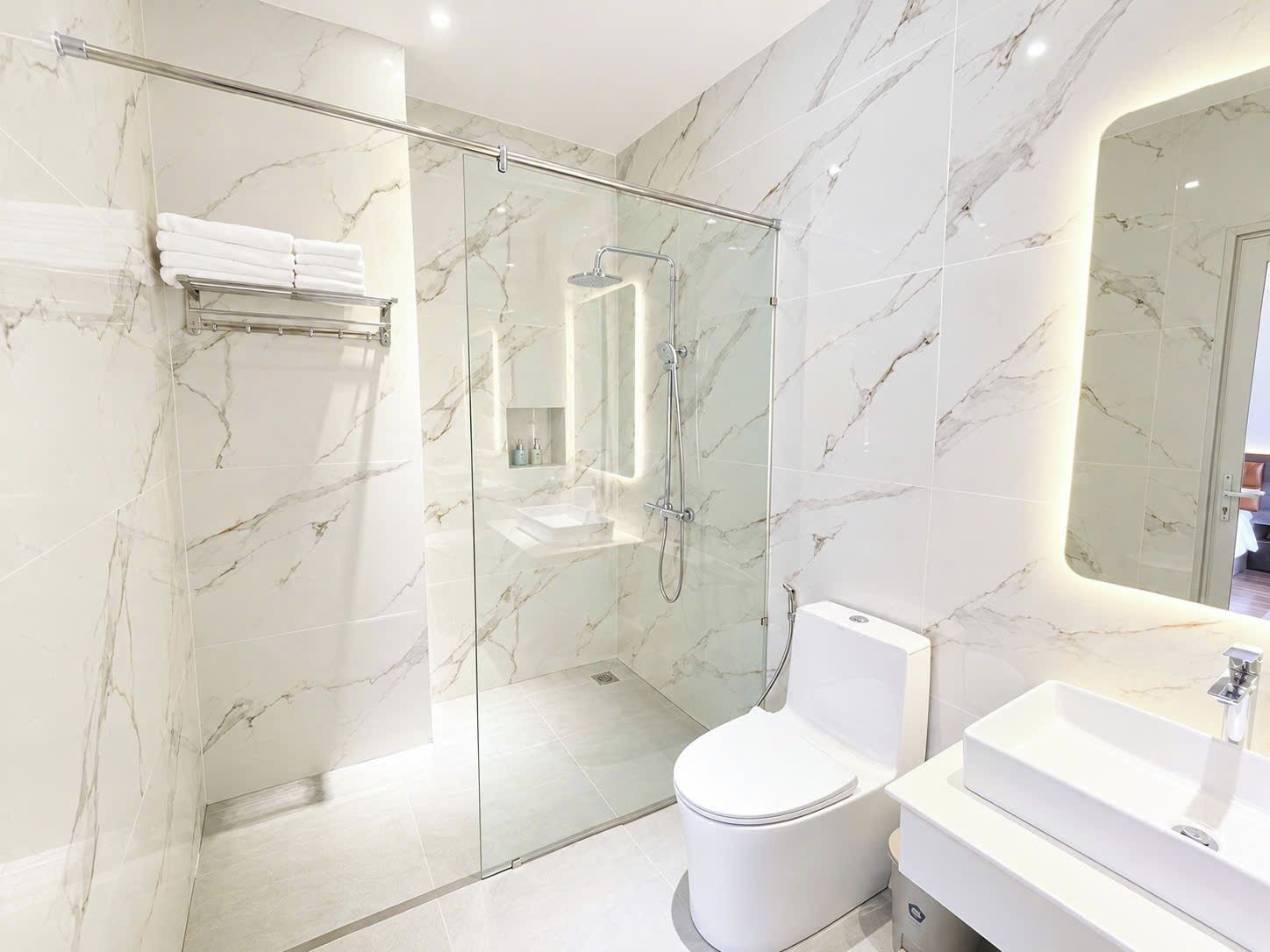 A modern bathroom with a glass-enclosed shower, a white toilet, and a vanity with a sink.