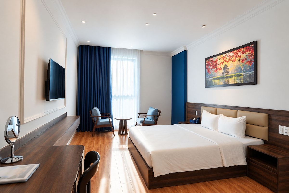Ein Hotelzimmer mit Bett, Schreibtisch, Stuhl, kleinem Tisch und Fernseher.