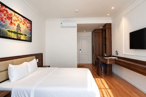 Habitación de hotel con cama, escritorio, televisor y un cuadro en la pared.