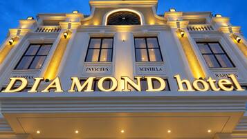 The exterior of the Diamond Hotel with illuminated signage and classical architectural details.