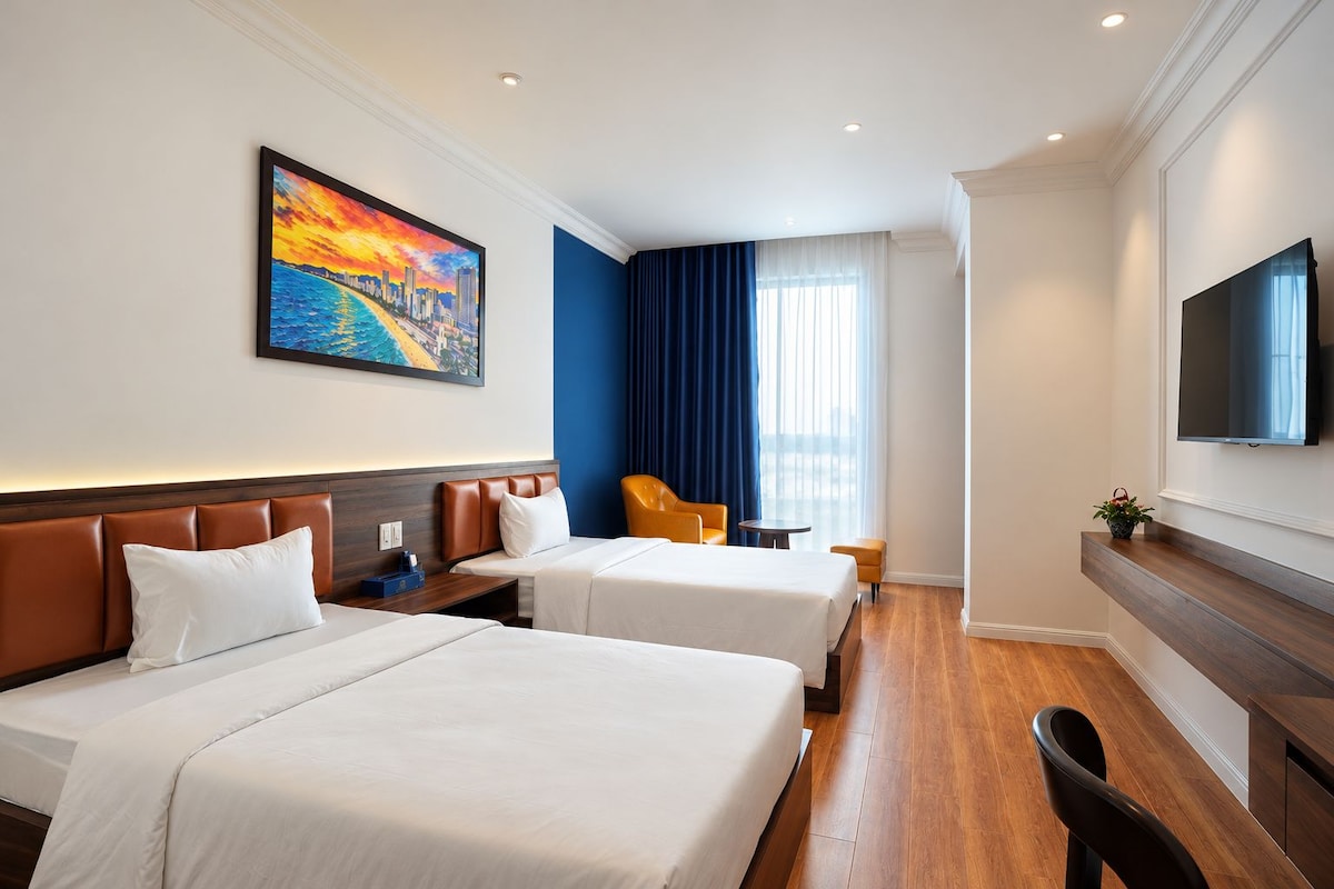 A hotel room with two beds, a TV, a painting, and a window with curtains.