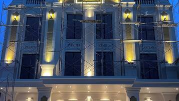 Un edificio de varios pisos con una entrada imponente, ventanas amplias y una fachada bien iluminada.