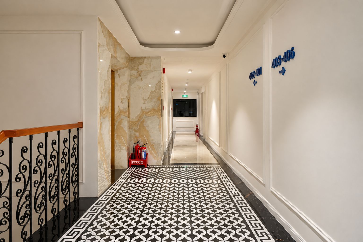 Un pasillo de hotel con pared de mármol, piso estampado y extintor.