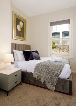 A bedroom with a bed, bedside table, lamp, and a window with a view. - Charming 2BD Near ICC, Casino and Darling Harbour (Pyrmont)
