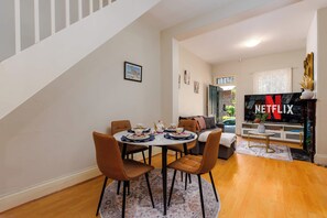 A modern living room with a dining area, a staircase, and a TV displaying the Netflix logo. - Pet Friendly Haven | Walk to D Harbour, Star & ICC (Pyrmont)