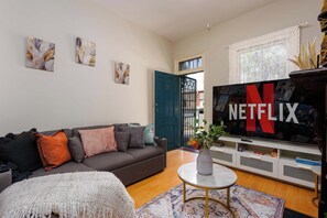 A living room with a sofa, a coffee table, a TV, and artwork on the wall. - Pet Friendly Haven | Walk to D Harbour, Star & ICC (Pyrmont)