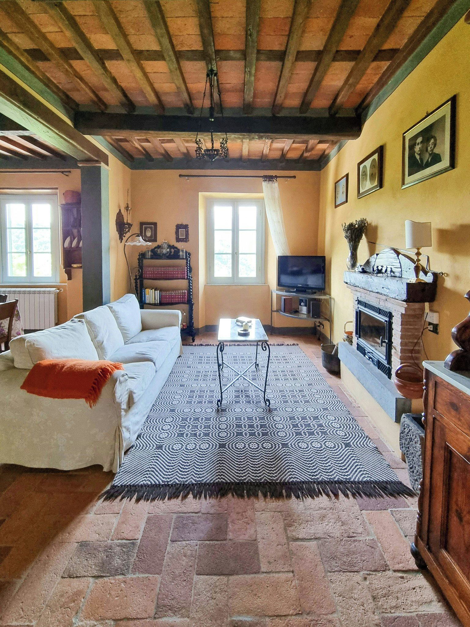 A cozy living room with a sofa, a patterned rug, a fireplace, and a television.
