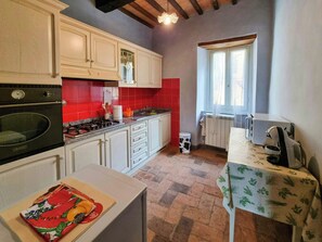 Eine Küche mit Herd, Backofen und einem Fenster mit Vorhängen.