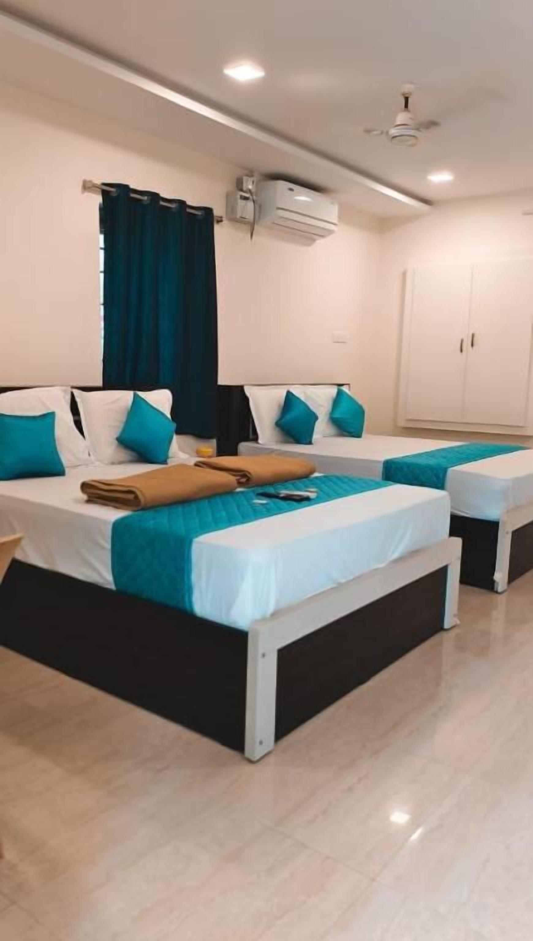 A hotel room with two beds, a ceiling fan, an air conditioning unit, and a wardrobe.