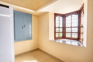 A room with a blue wardrobe, a corner window with wooden frames, and a white refrigerator. - Rch Home Stay (Rameswaram)