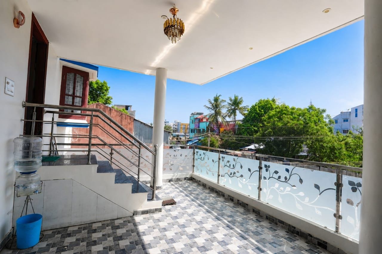 A balcony with a checkered floor, a staircase, and a railing with floral designs.