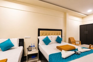 A hotel room with two beds, a wardrobe, a nightstand with a kettle, and a chair. - Rch Home Stay (Rameswaram)