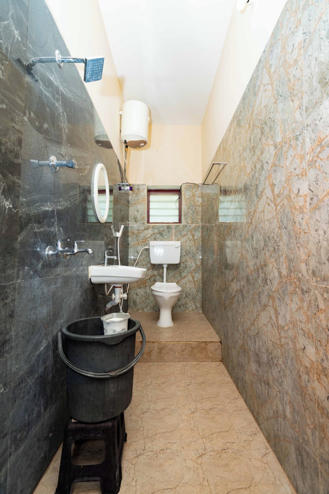 A bathroom with a marble floor, a sink, a toilet, and a shower area.