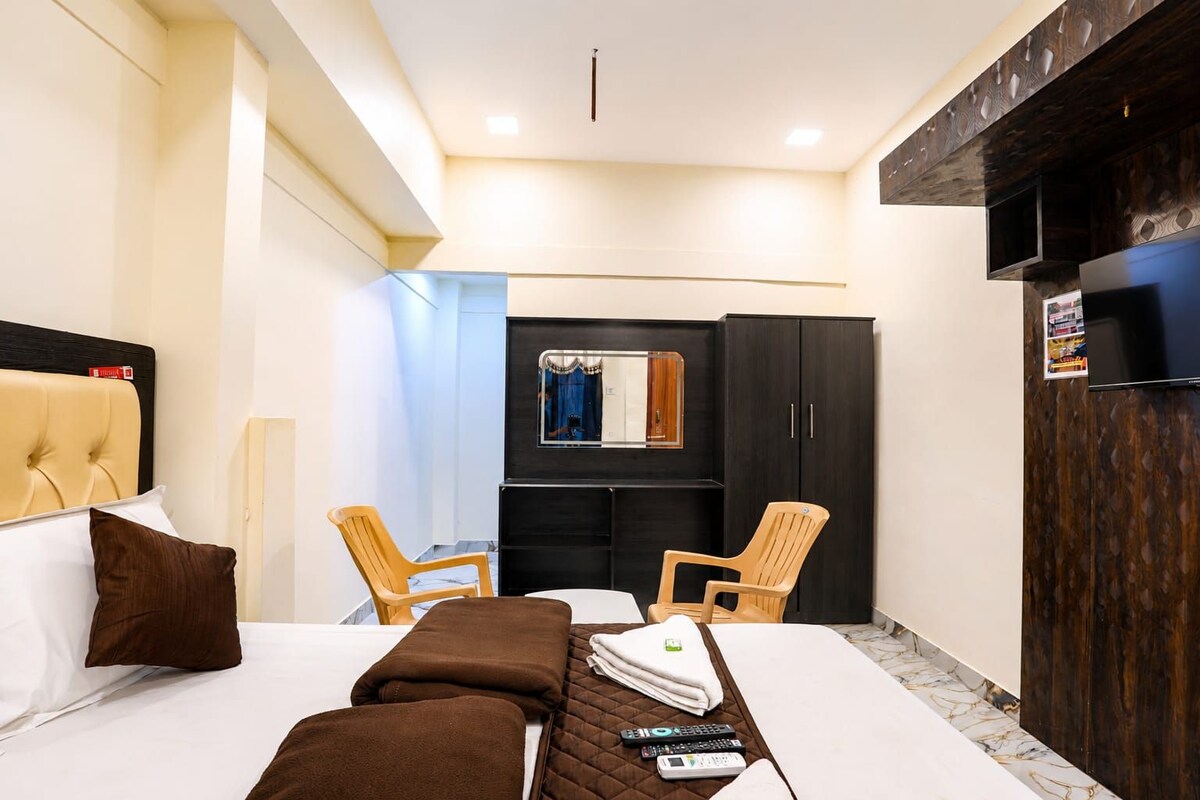 Una habitación de hotel con cama, dos sillas, un armario y televisión.