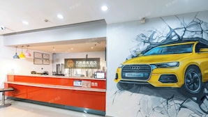 Ein Hotelrezeptionstresen mit Stadtbild-Wandgemälde und einer Illustration eines gelben Autos.