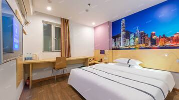 Habitación de hotel con cama, escritorio, silla y un mural con vista a la ciudad.