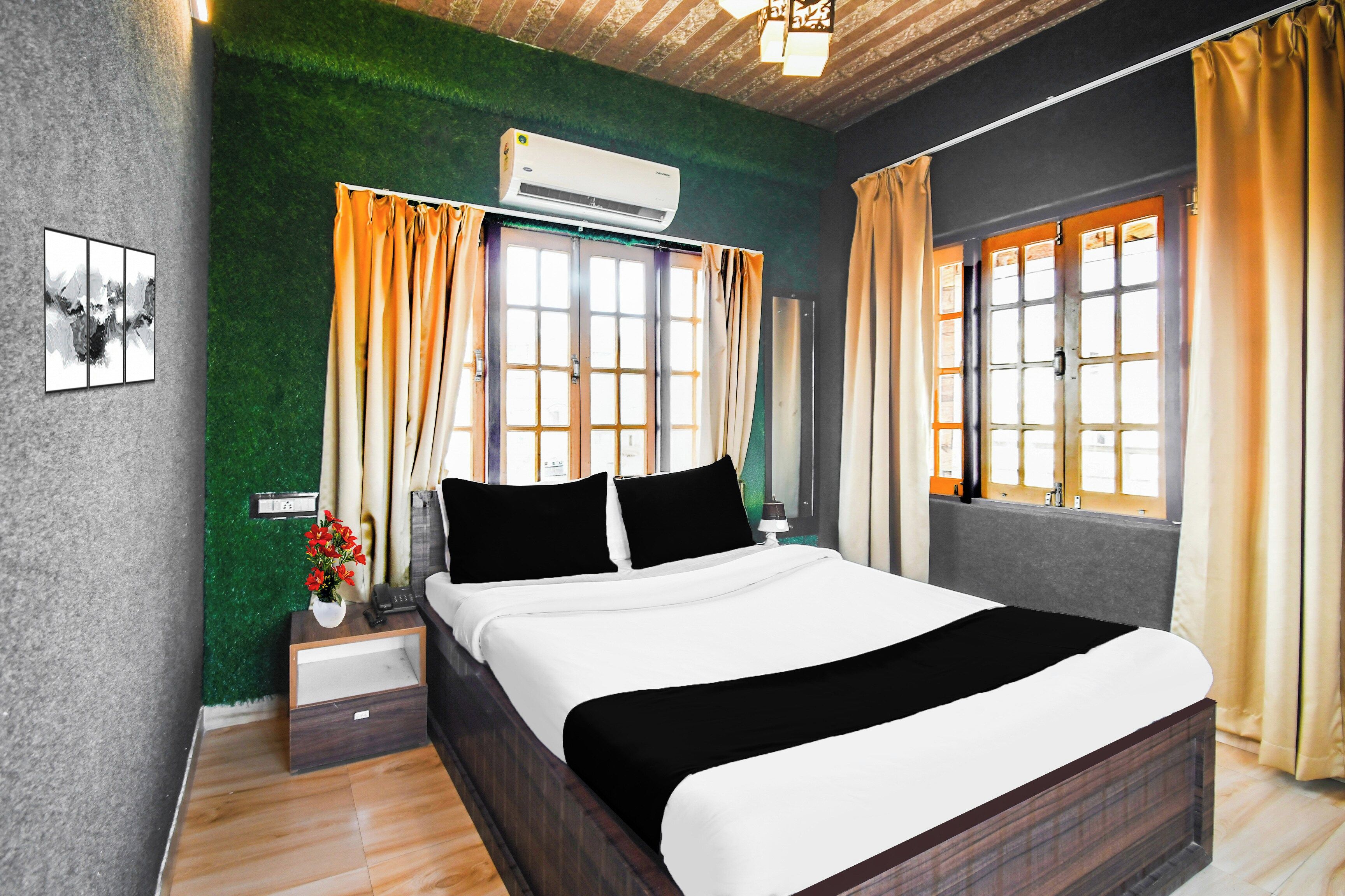 Habitación de hotel con cama, mesitas de noche, aire acondicionado instalado en la pared y una ventana con cortinas.