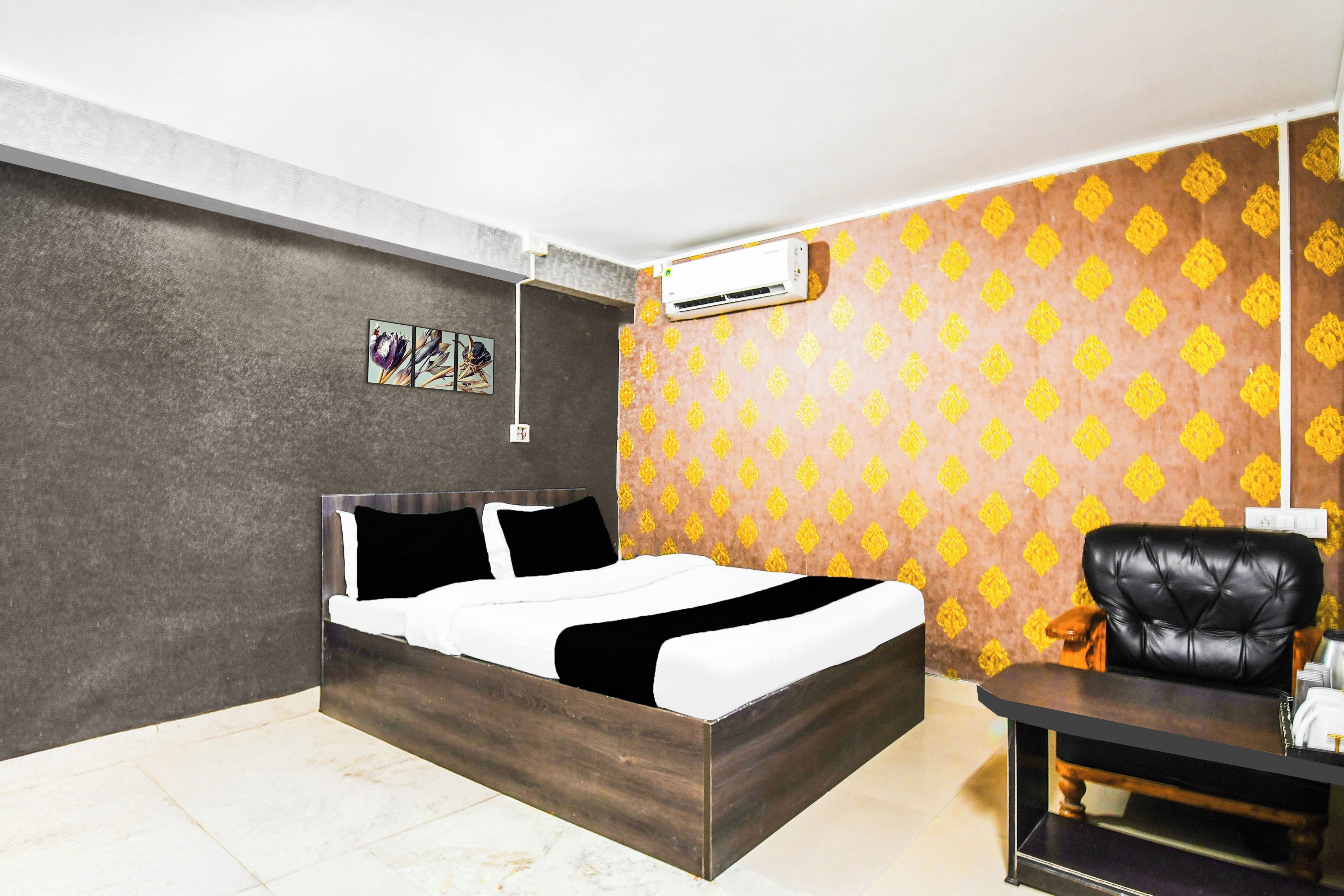 A bedroom with a bed, a chair, an air conditioning unit, and a patterned wall.