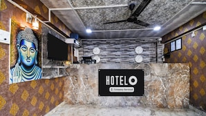 Zona de recepción de hotel con un mural de Buda, un reloj y un letrero que indica servicio de empresa.