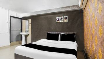 Habitación de hotel con una cama, un lavamanos y aire acondicionado instalado en la pared.