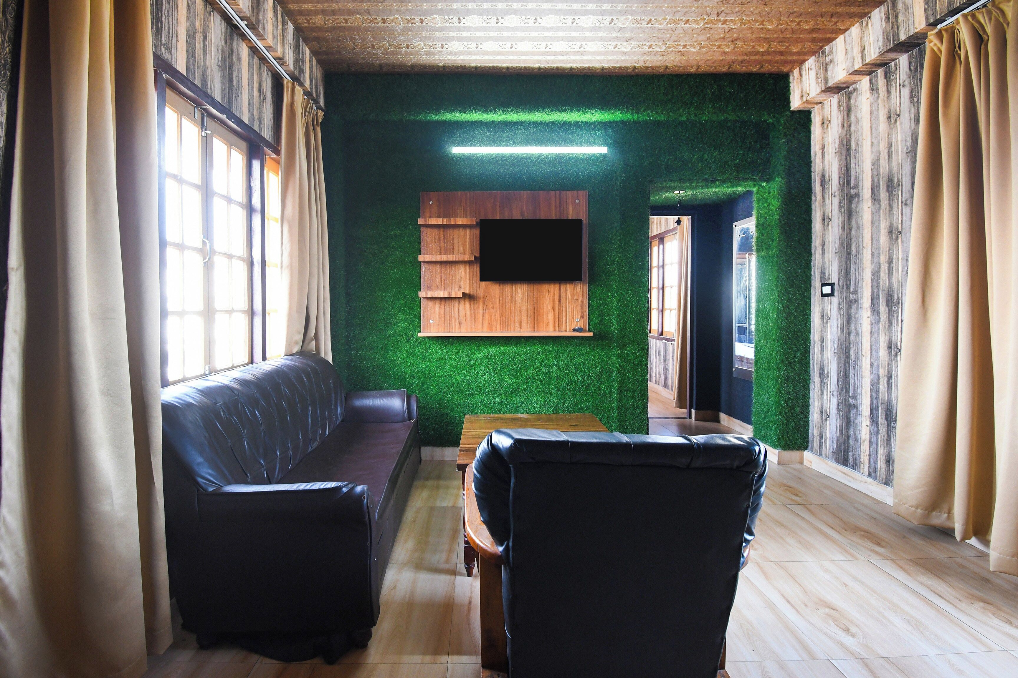 A room with a wooden floor, a sofa, a table, and a flat-screen TV mounted on a wall.