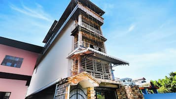 A multi-story building with a prominent tower section, a gated entrance, and a balcony with a metal railing.