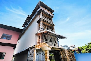 A multi-story building with a prominent tower section, a gated entrance, and a balcony with a metal railing. - Hotel O Champasari Siliguri (Siliguri)