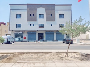 A multi-story building with a flat facade, several windows, and a ground-level entrance with a closed shutter. - Al Madinah Residential Apartments (Madinah)