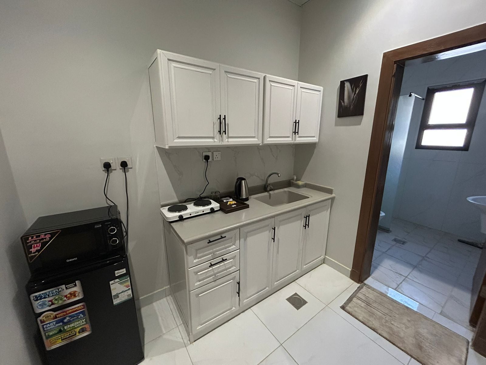 A compact kitchen with white cabinets, a built-in stove, and a sink.