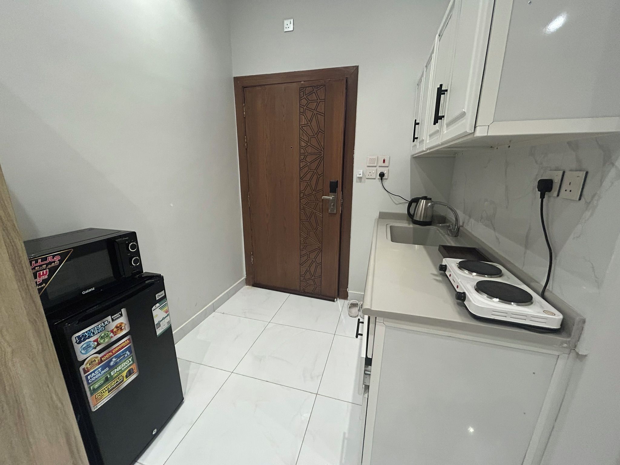 A compact kitchen with a refrigerator, a stove, and a sink.