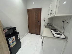A compact kitchen with a refrigerator, a stove, and a sink. - Al Madinah Residential Apartments (Madinah)