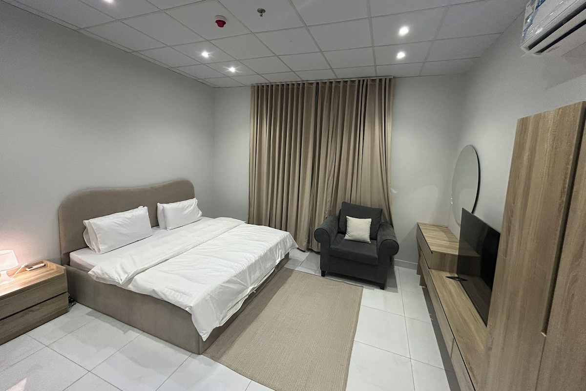 Une chambre d’hôtel avec un lit, une chaise, une télévision et un miroir.