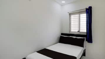 A small, single-bed room with a window and a curtain.