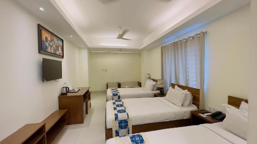 Une chambre d’hôtel avec deux lits, un bureau, une télévision et un ventilateur de plafond.