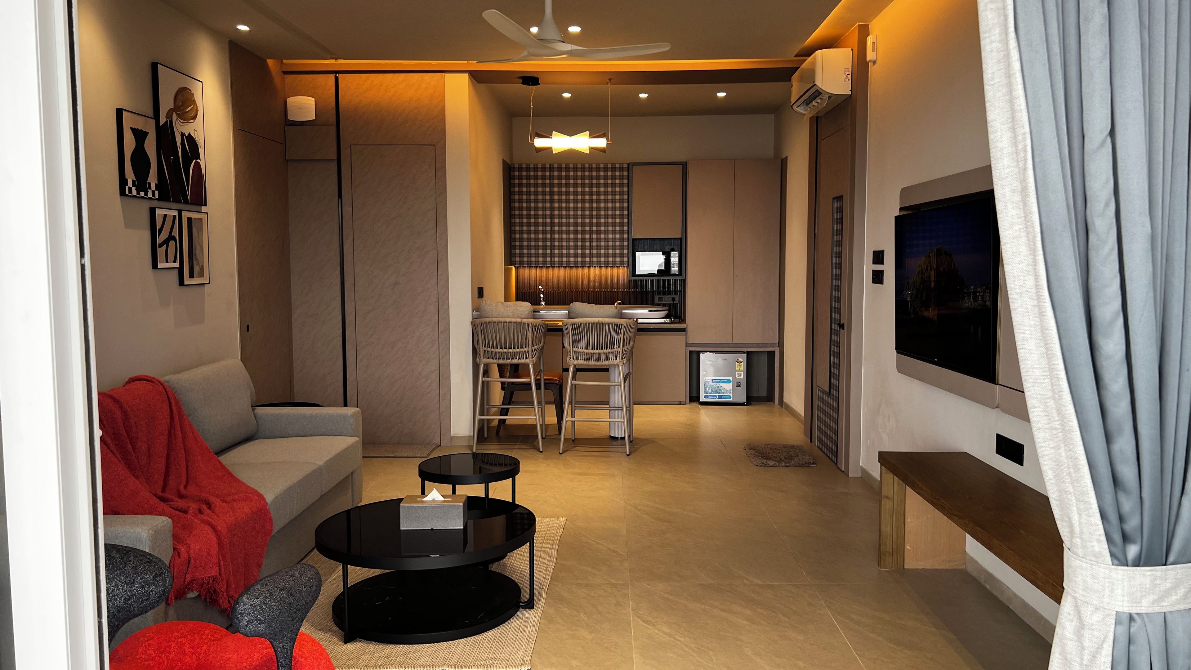Una sala de estar moderna con un sofá, una mesa de centro y un televisor. Cuenta con una zona de cocina con una mesa de comedor y sillas.
