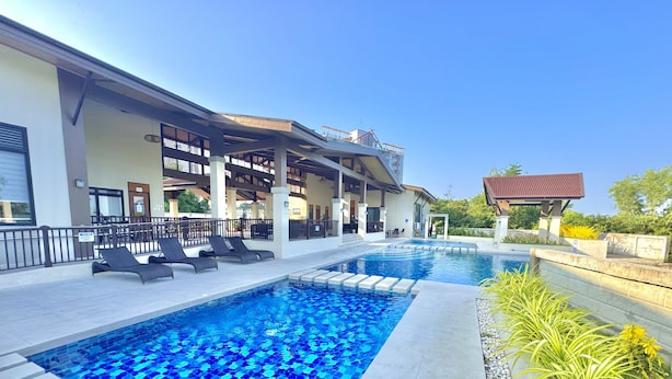 Piscina com espreguiçadeiras, área de estar coberta e um pequeno pavilhão.