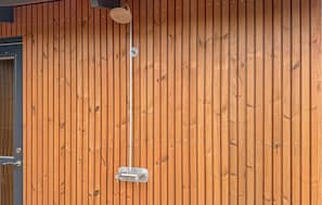 Eine Holzwand mit einer Metallvorrichtung, möglicherweise einer Lampe oder einem Sensor, und einer Tür mit Griff.