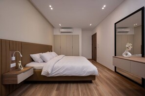 A modern bedroom with a bed, bedside table, mirror, wardrobe, and built-in air conditioning unit. - Amazing Deal at Elevens by Spacey #16 (cairo)