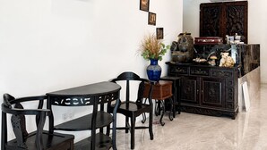 A modern kitchen with a flat-screen TV, a dining area with a table and chairs, and a decorative cabinet with traditional items. - SRG Indira Hotel (Gelang Patah)
