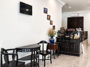 Una cocina moderna con un televisor de pantalla plana, un comedor con mesa y sillas, y un mueble decorativo con objetos tradicionales.