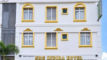 A multi-story hotel with a prominent sign reading 'SRG INDIRA HOTEL' and a brown awning below.