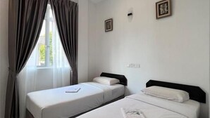 A hotel room with two beds, a window with curtains, and a small picture on the wall. - SRG Indira Hotel (Gelang Patah)