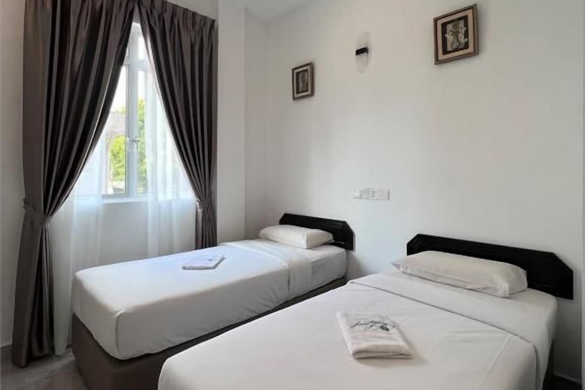 Una habitación de hotel con dos camas, una ventana con cortinas y un cuadro pequeño en la pared.