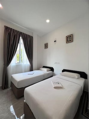 Una habitación de hotel con dos camas, una ventana con cortinas y un cuadro pequeño en la pared.