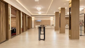 Un amplio vestíbulo de hotel con una mesa central, columnas imponentes y un candelabro.